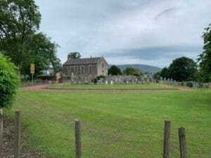 A church surrounded by trees with the Lamington Hills in the background